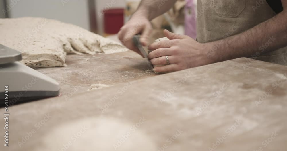 Male baker working in bakery kneading fresh dough on kitchen counter Male baker working in bakery kneading fresh dough on kitchen counter