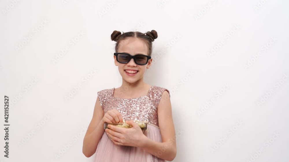 teen girl with glasses to watch funny 3D movies eats popcorn against white wall. teen girl with glasses to watch funny 3D movies eats popcorn against white wall.