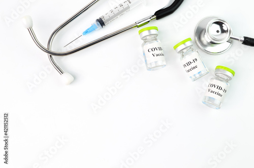 Syringe, stethoscope and Covid-19 bottle vaccination over white background.