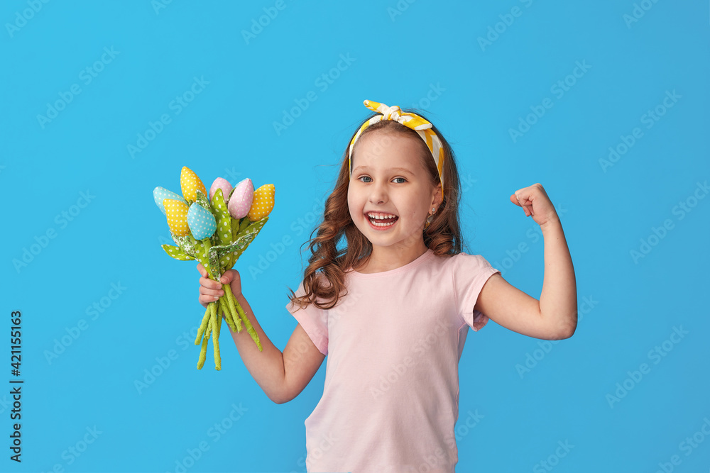 charming little girl with curly hair and bandage on her head holds out bouquet colorful tulips made fabric. child smiles and shows his strength, muscles on blue background studio. concept female power charming little girl with curly hair and bandage on her head holds out bouquet colorful tulips made fabric. child smiles and shows his strength, muscles on blue background studio. concept female power