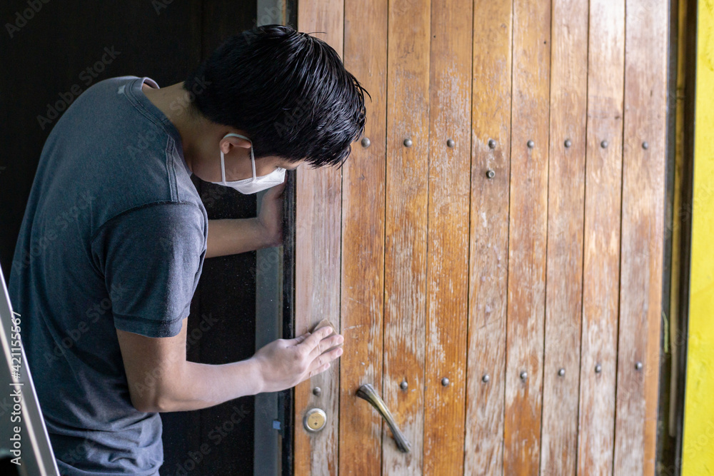 young man passing sandpaper to wooden door to apply paint young man passing sandpaper to wooden door to apply paint