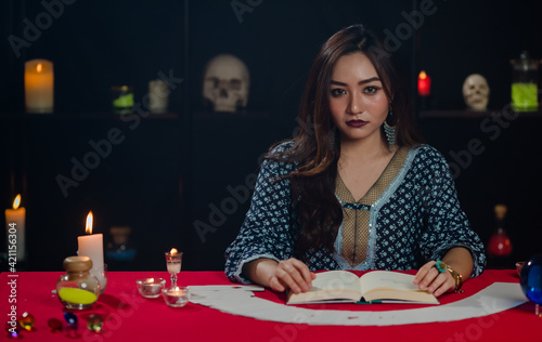 Asian sorceress reading fortune in book