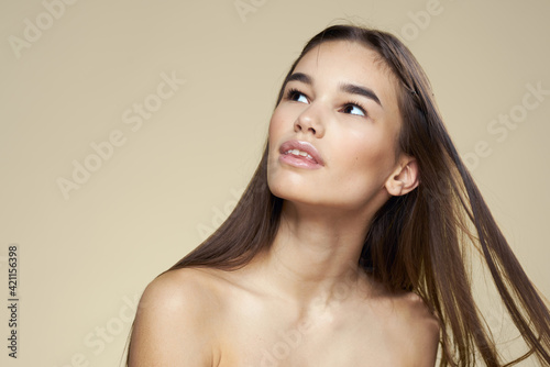 Pretty woman naked shoulders long hair body care beige background