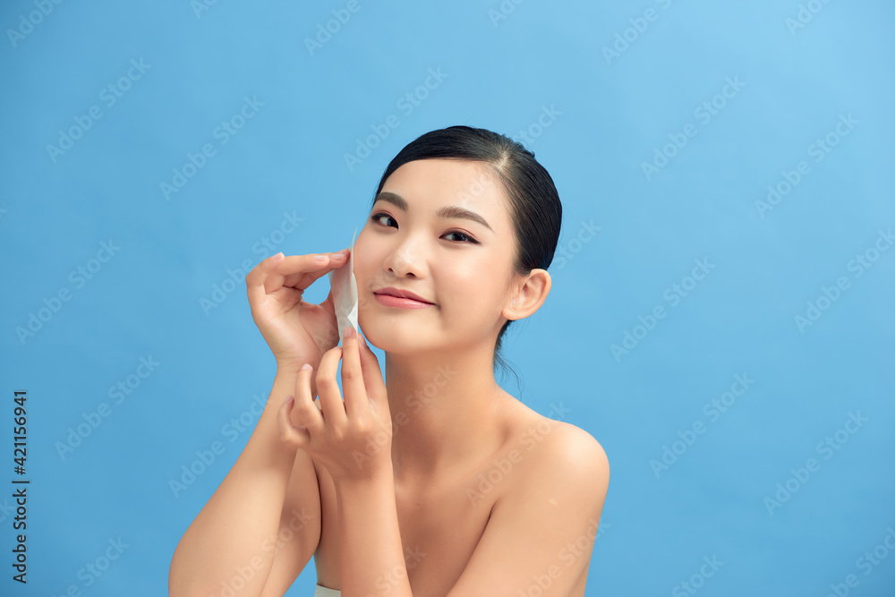 Woman removing oil from face using blotting papers Woman removing oil from face using blotting papers