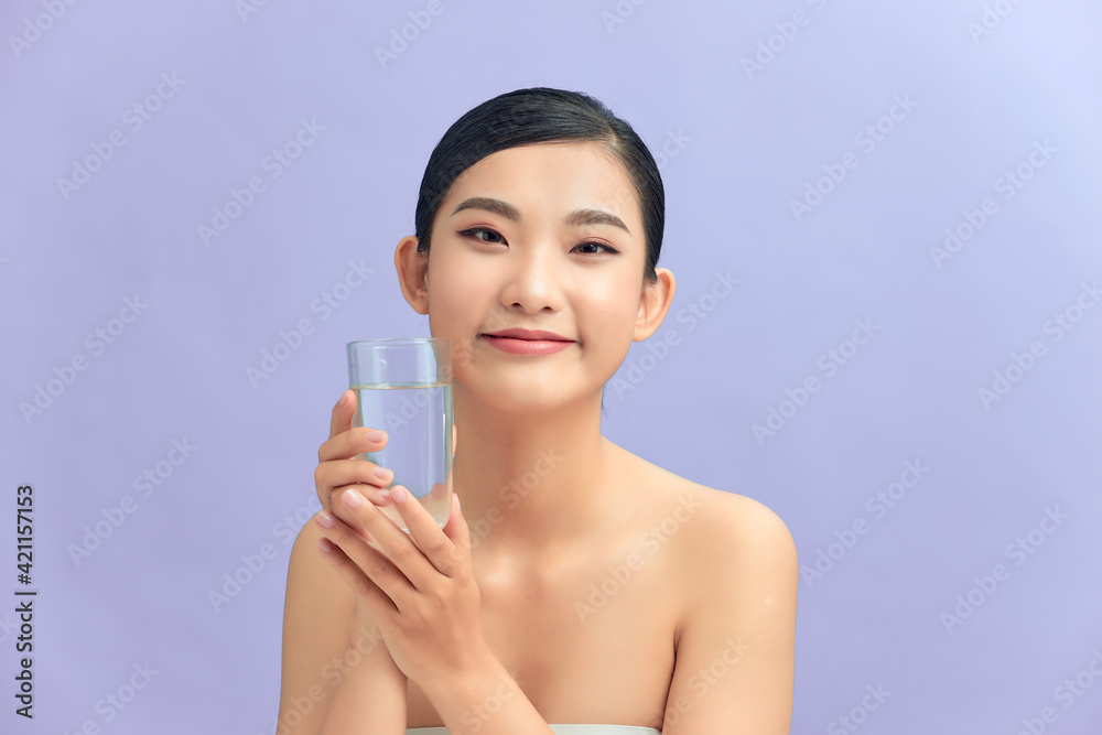 Attractive woman drinking water against purple background Attractive woman drinking water against purple background