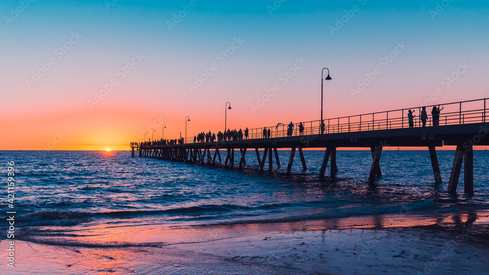Glenelg Beach beach foreshore view with people walking along the pier at sunset, South Australia