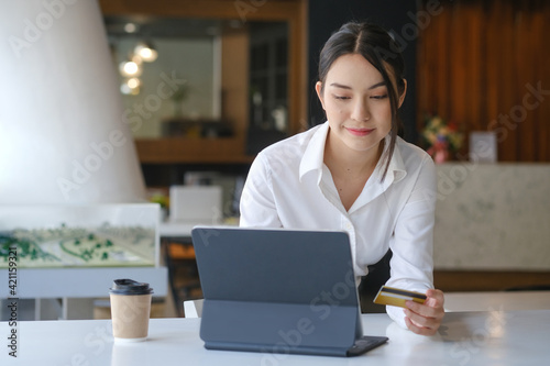 Attractive woman holding credit card and using computer tablet for online payment or online shopping.