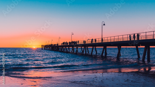 Glenelg Beach beach foreshore view with people walking along the pier at sunset  South Australia