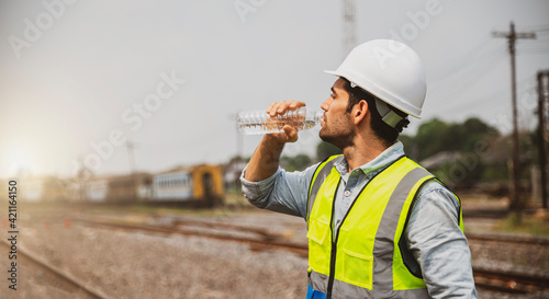 Caucasian man railway engineer drink water from bottle in the site work of train garage.