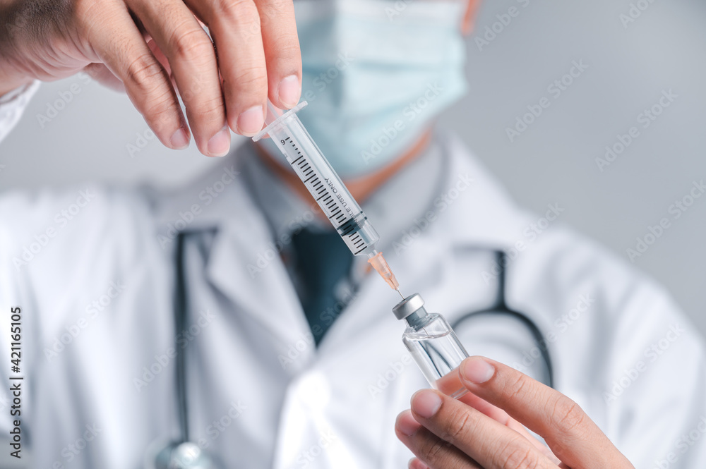 Doctor or scientist carries a syringe and a vaccine against COVID-19, vaccination and laboratory experiments. Concept of protection against the COVID-19 virus. Doctor or scientist carries a syringe and a vaccine against COVID-19, vaccination and laboratory experiments. Concept of protection against the COVID-19 virus.