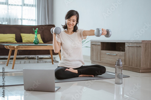 Young girl looking at laptop and doing exercises at home by her self