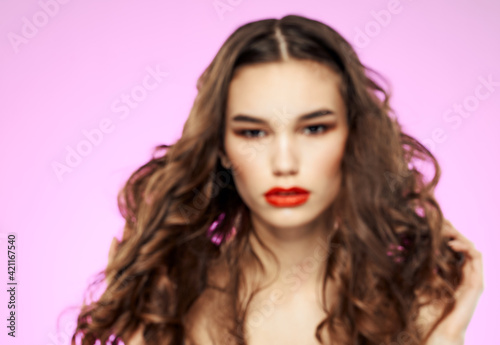 Charming brunette with curly hair on a pink background portrait cropped view close-up