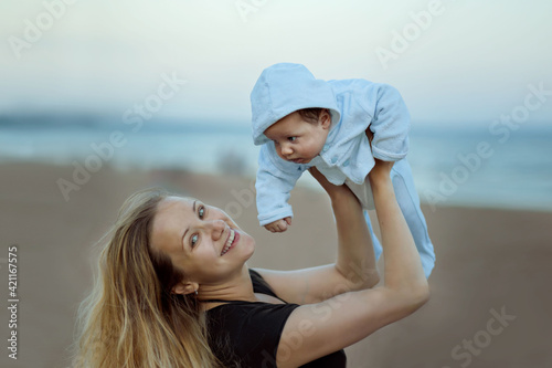 young caucasian blond haired woman holding cute baby boy on the beach. Natural beauty. Family concept. Image with selective focus