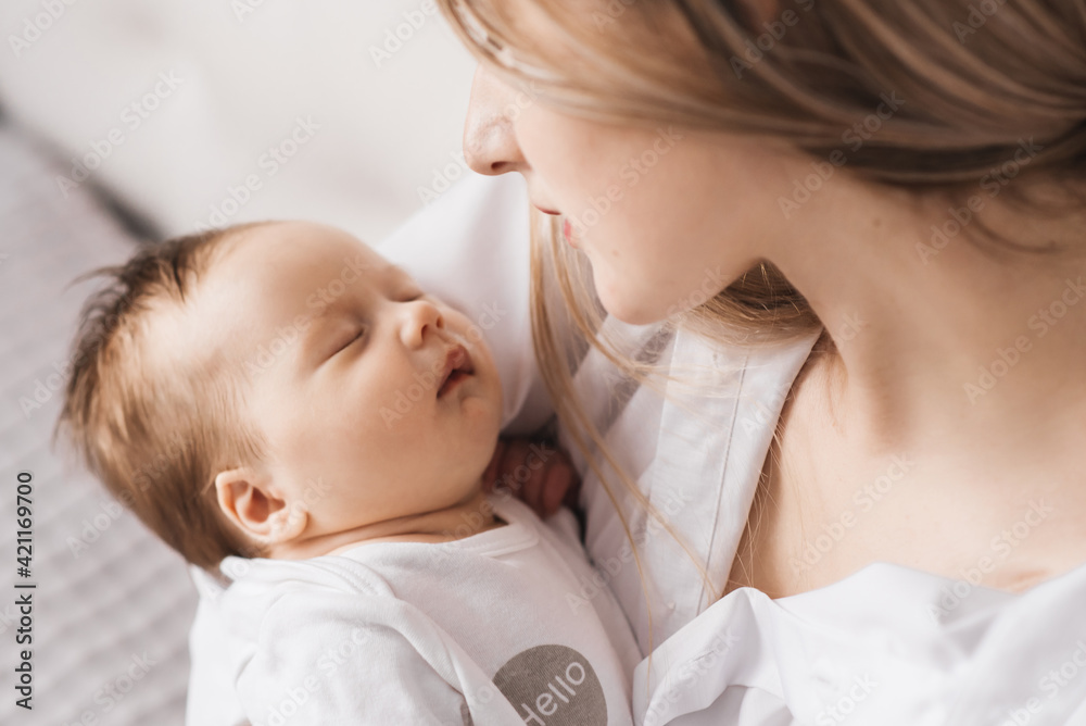 A loving mother carries her newborn baby at home. portrait of a happy mother holding a sleeping baby in her arms. Mother hugs her little 4-month-old daughter A loving mother carries her newborn baby at home. portrait of a happy mother holding a sleeping baby in her arms. Mother hugs her little 4-month-old daughter