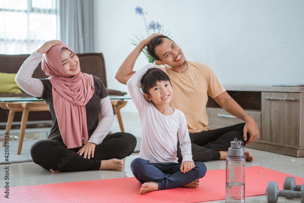 beautiful asian muslim family exercising at home together. parent and child doing sport stretching in livingroom beautiful asian muslim family exercising at home together. parent and child doing sport stretching in livingroom