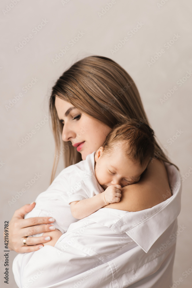 A loving mother carries her newborn baby at home. portrait of a happy mother holding a sleeping baby in her arms. Mother hugs her little 4-month-old daughter