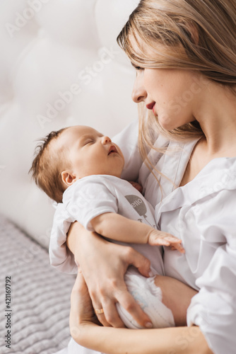 A loving mother carries her newborn baby at home. portrait of a happy mother holding a sleeping baby in her arms. Mother hugs her little 4-month-old daughter