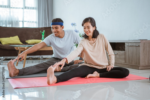 Asian fitness couple, man and woman exercising together at home doing yoga in livingroom