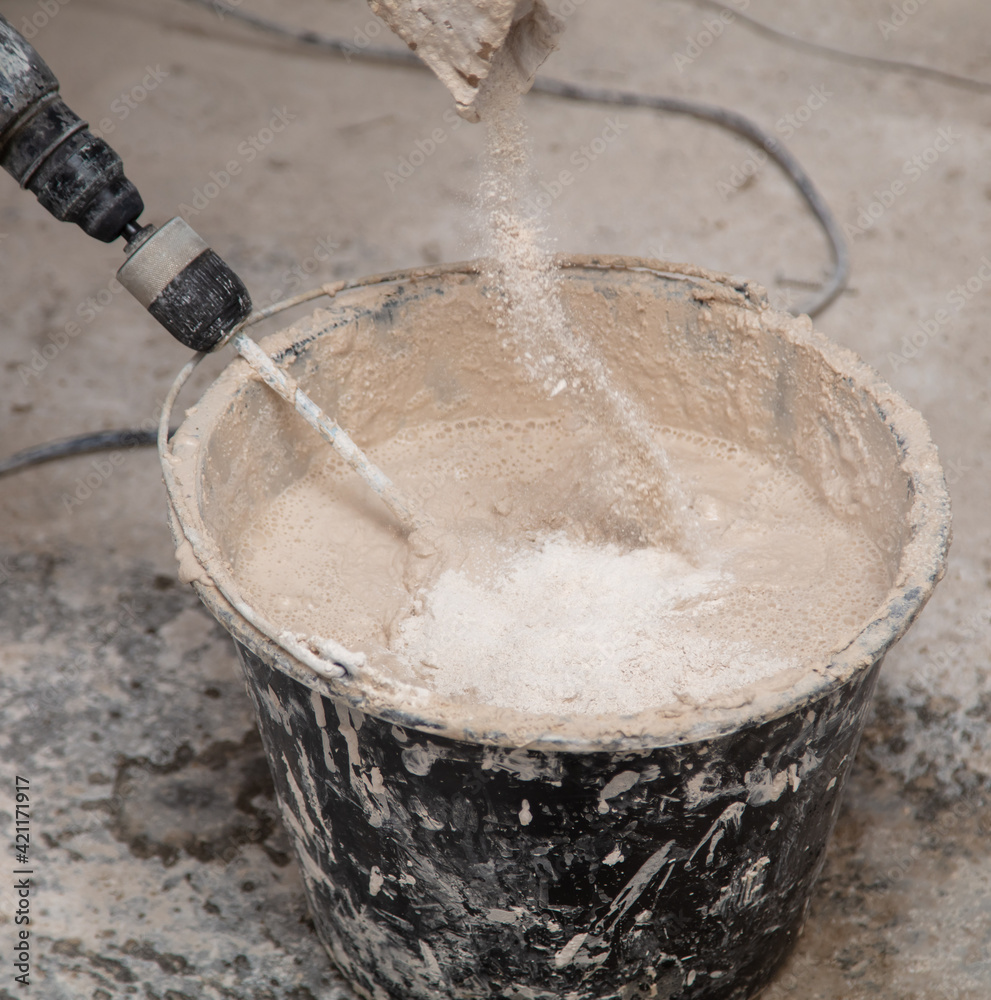 A worker kneads the mixture into plaster buckets. Home renovation A worker kneads the mixture into plaster buckets. Home renovation