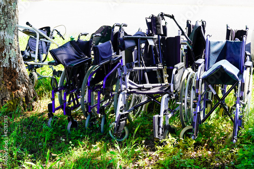 few empty wheelchairs old wheelchairs are left behind after being used by deceased elderly people photo