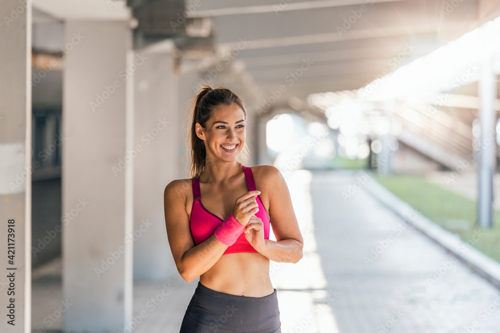 Young female worming up before fitness training session . Healthy young woman warming up outdoors. She is stretching her arms and looking away. Young female worming up before fitness training session . Healthy young woman warming up outdoors. She is stretching her arms and looking away.