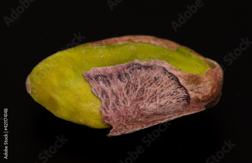 Close-up of fresh pistachio nuts on a black background.