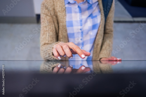 Woman using interactive touchscreen display of electronic multimedia kiosk at modern museum or exhibition - close up top view. Education, learning and technology concept