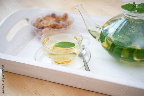 Fresh brewed mint tea on tray with teacup teapot and candi sugar healthy living