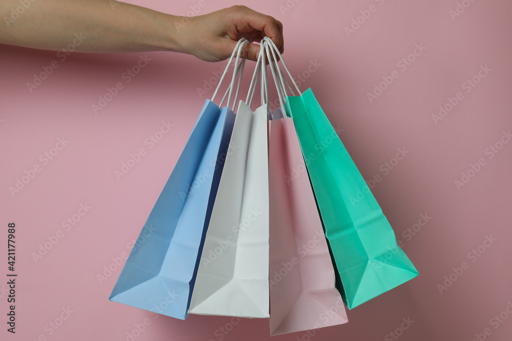 Female hand hold paper bags on pink background