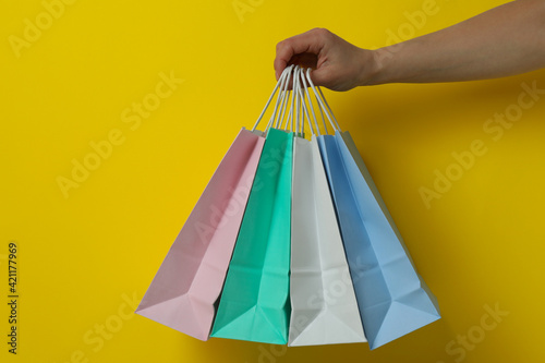 Female hand hold paper bags on yellow background