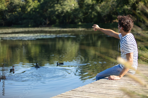 Fototapeta Naklejka Na Ścianę i Meble -  young happy man feeding ducks in the pond