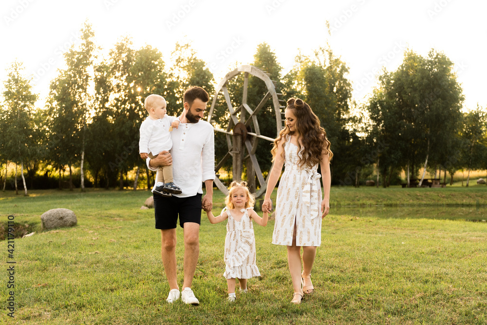 Fototapeta premium Happy man and woman play with children outside on a sunny day
