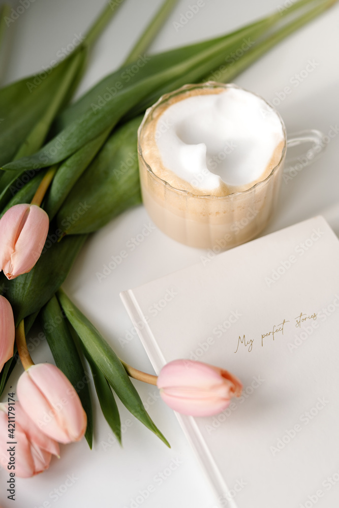 Cappuccino cup with planner and blush pink tulips. Work from home concept Cappuccino cup with planner and blush pink tulips. Work from home concept