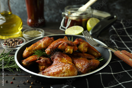 Concept of tasty food with baked chicken wings on wooden background