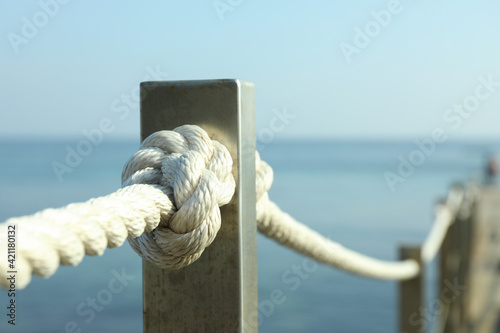 Handrail with ropes against sea, close up