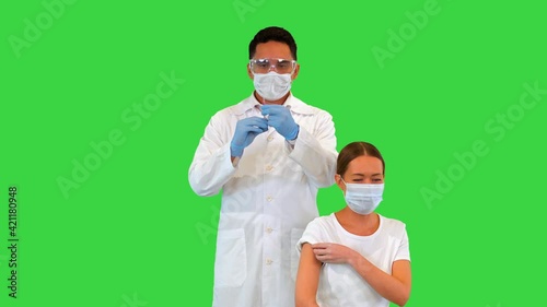 Doctor making an injection to patient in a medical mask on a Green Screen, Chroma Key. photo