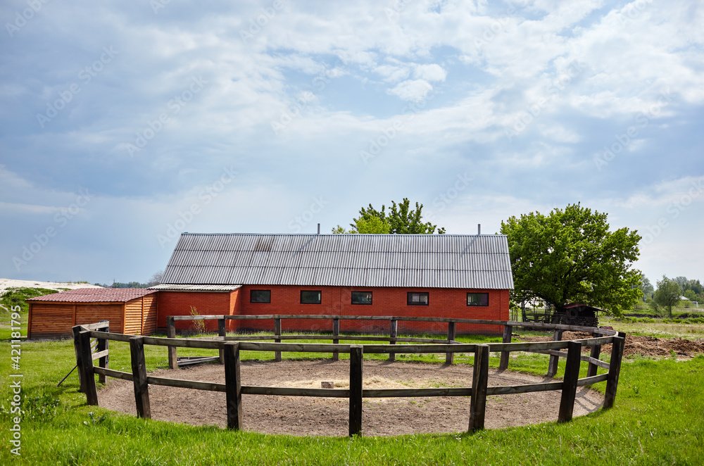Wooden corral for horse dressage against a blue sky on a sunny day. Grass paddock on farmland with wooden fence Wooden corral for horse dressage against a blue sky on a sunny day. Grass paddock on farmland with wooden fence