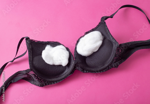 black female bra with cotton wool inside on a pink background. The concept of augmentation of the female breast with plastic surgery, mammoplasty photo