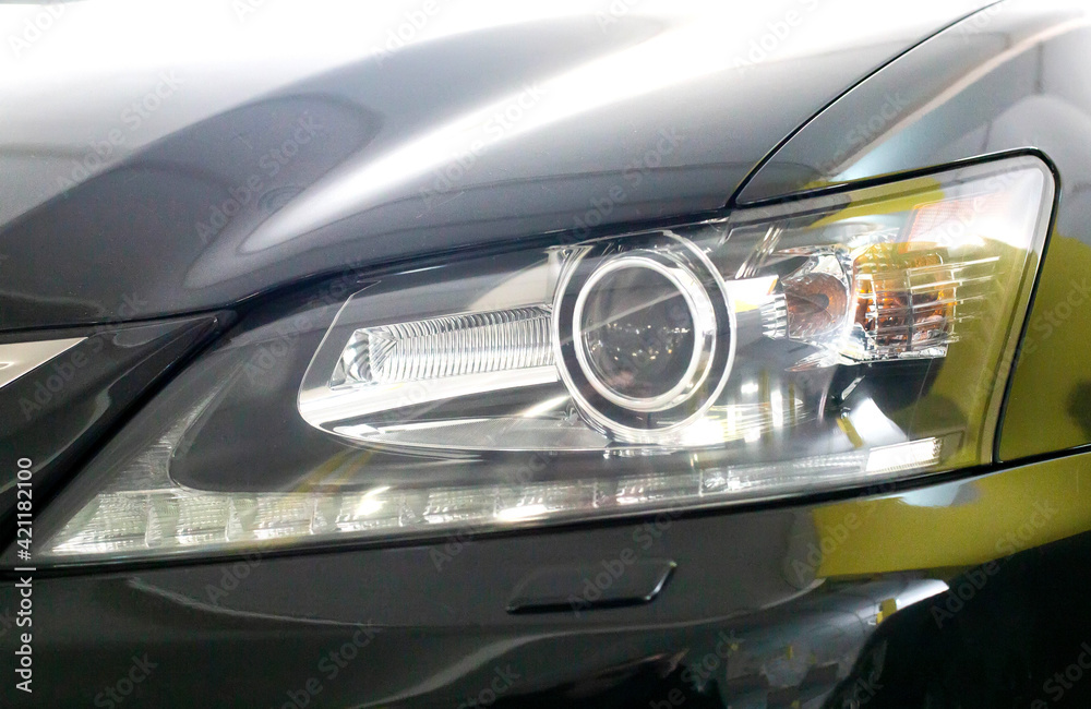 Headlight of a black car. Xenon with lens, modern, close-up