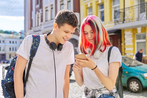 Handsome teenagers couple guy and girl together on city street looking in smartphone screen © Valerii Honcharuk