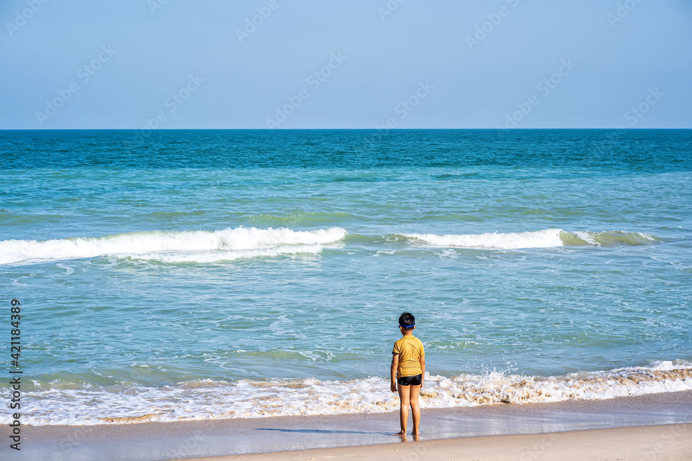 A boy standing on the beach in the morning on a fine day. A boy standing on the beach in the morning on a fine day.