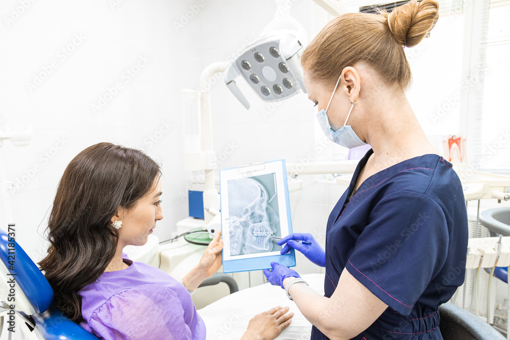 Dentistry concept. Professional dental services and modern equipment without pain. The doctor consults and treats the young woman, conducts an examination and draws up a treatment plan Dentistry concept. Professional dental services and modern equipment without pain. The doctor consults and treats the young woman, conducts an examination and draws up a treatment plan