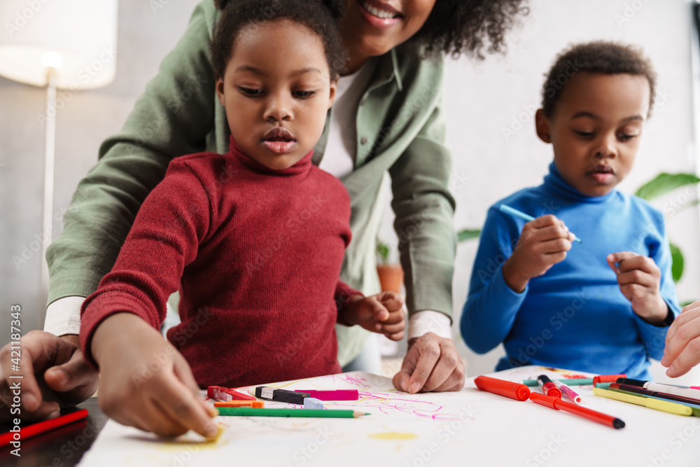 Happy afro american mother smiling while drawing with her children