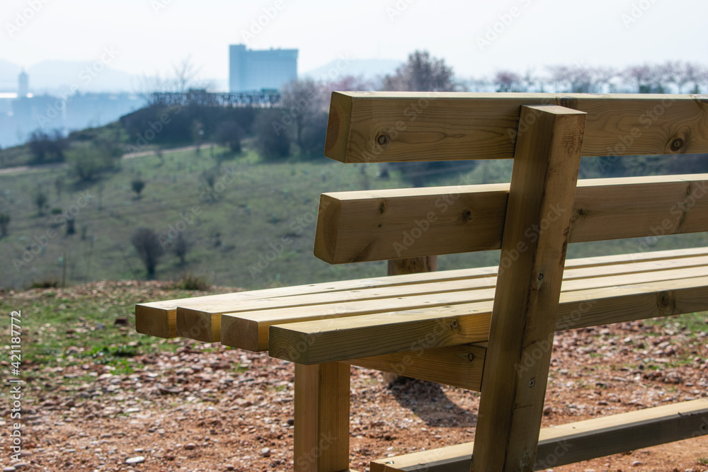 close empty wooden bench in spring park over the city
