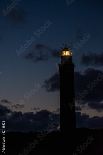 Lighthouse standing on the Dutch coast with a dramatic. and colorful dusk or dawn sky behind it. High quality photo