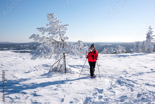 Woman snowshoeing in winter forest in Lapland Finland