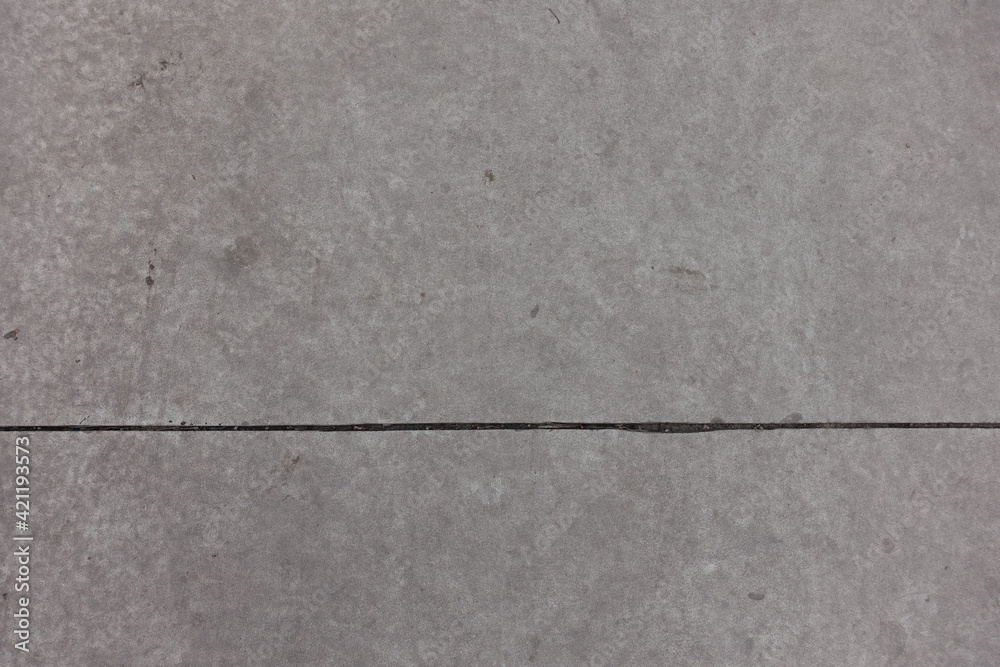 Gray concrete slab with joint dividing it in two uneven parts