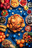 New year dinner table. Roasted Christmas chicken with orange slices, cranberries, garlic, festive decoration, candles, tangerine, pomegranate, golden glitter stars on blue background