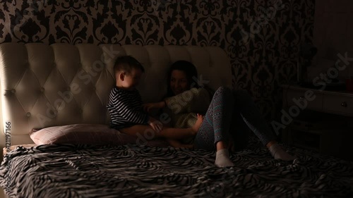 Mother with child read a book in the dark, before bedtime
