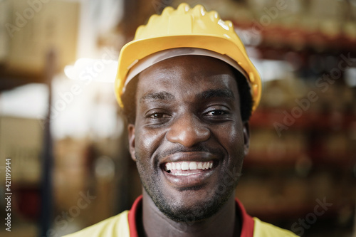 Portrait of happy african worker man looking at camera inside warehouse store - Focus on face